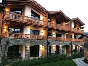 A multi-story building with balconies, stone arches, and outdoor seating.