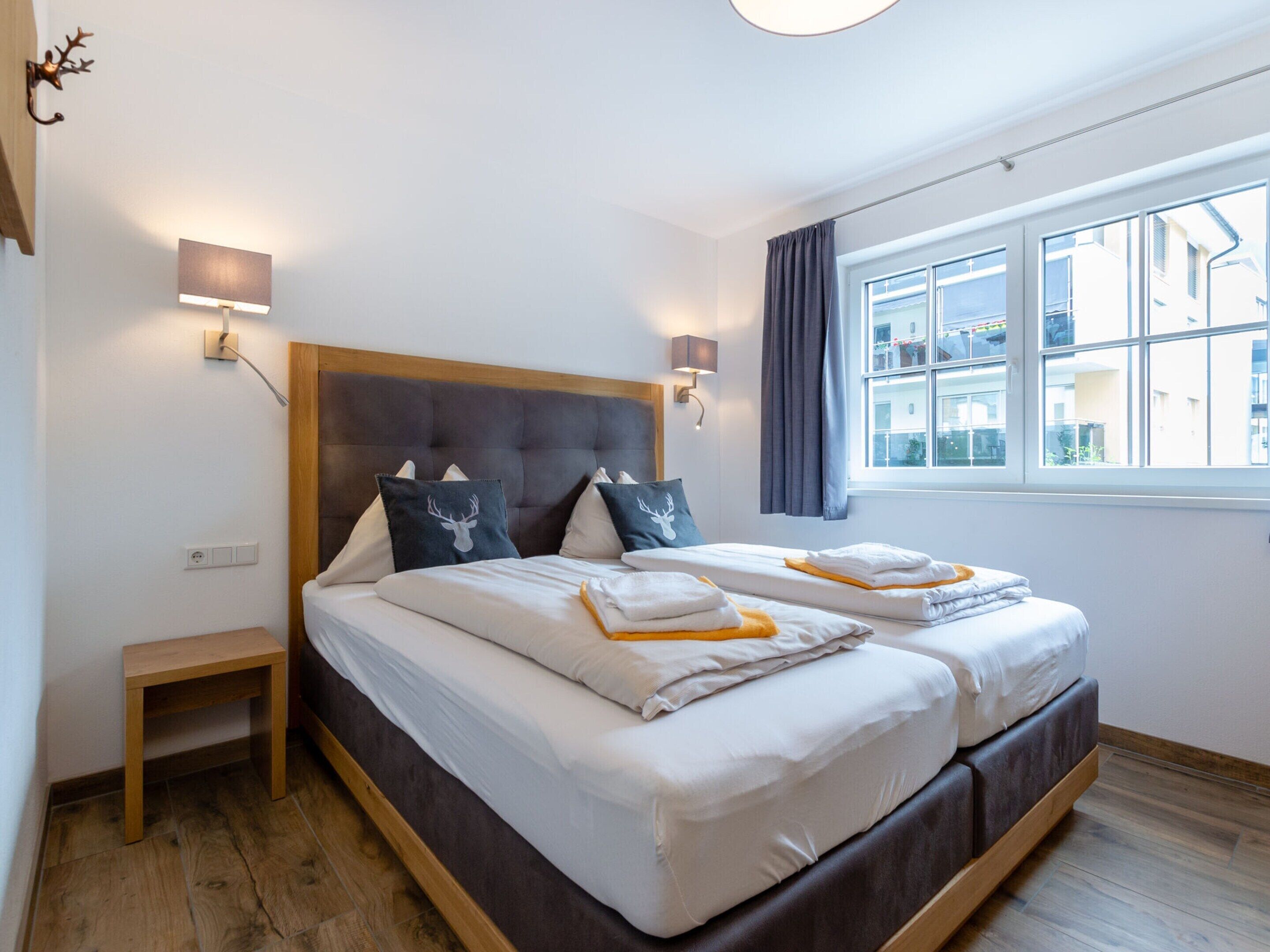 Ein Doppelbett mit Holzkopfstück, zwei Nachttische und ein Fenster mit Vorhängen.