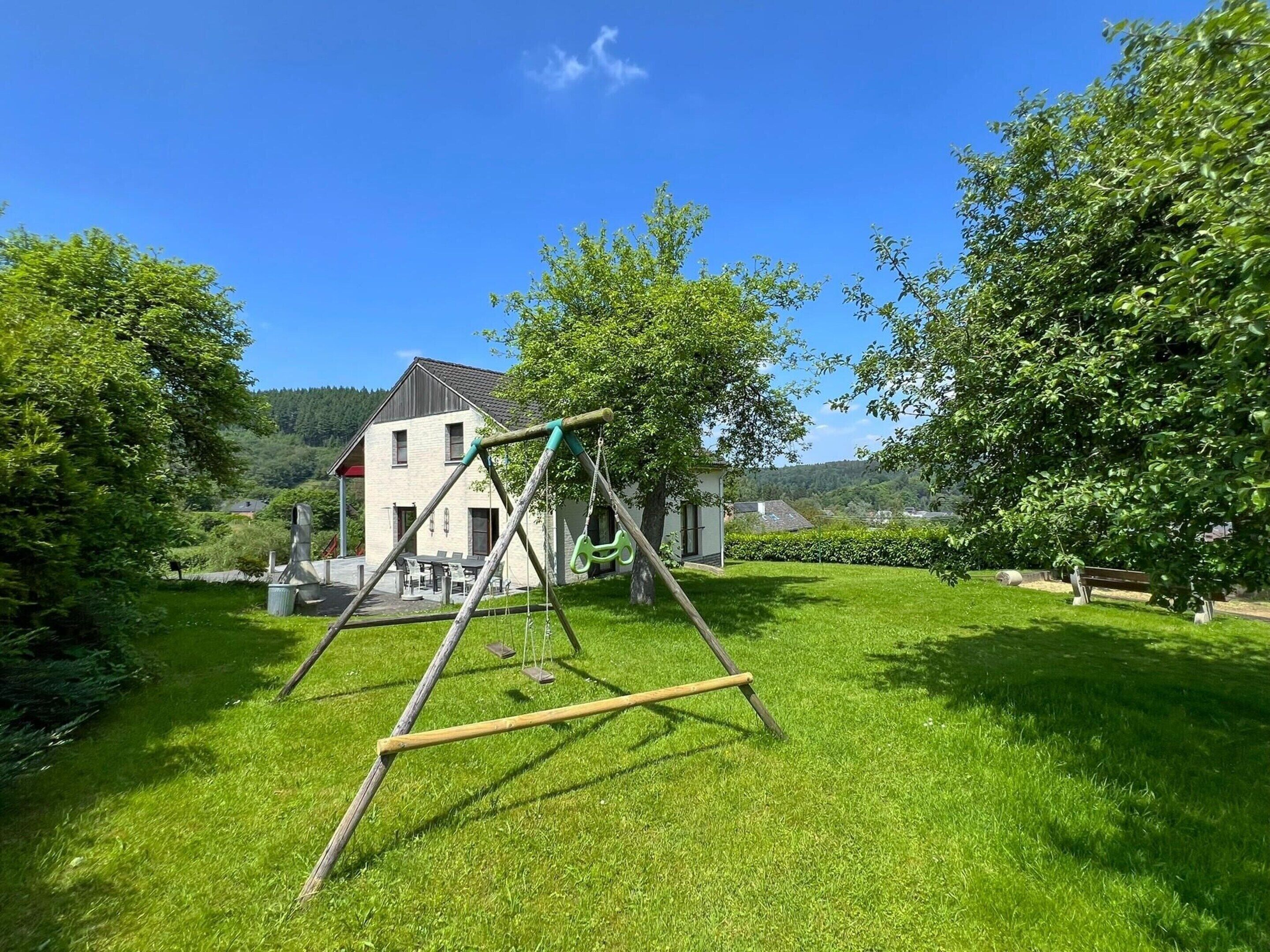 Ein Rasen mit Schaukel und einem Haus im Hintergrund.