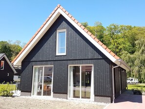A modern two-story building with a dark facade, white trim, and a red-tiled roof. It features large glass doors and windows, providing ample natural light. - Cozy House With a Dishwasher in the Middle of the Achterhoek (Almen)