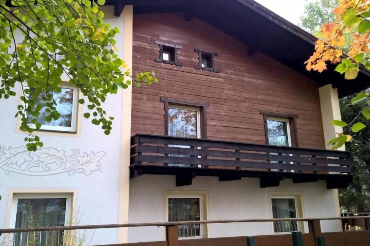 A two-story building with a wooden facade, a balcony, and a decorative wall design.