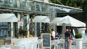 An outdoor cafe with white chairs and tables, a chalkboard menu, and potted plants. - Modern Suite With Combi-microwave, Close to Durbuy (Durbuy)