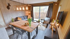 A modern dining area with a wooden table, grey upholstered chairs, a vase of tulips, and a mounted deer head. - Modern Suite With Combi-microwave, Close to Durbuy (Durbuy)