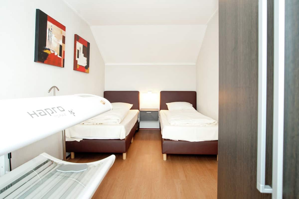 Une chambre d’hôtel avec deux lits, un luminaire au plafond et des œuvres d’art accrochées aux murs.