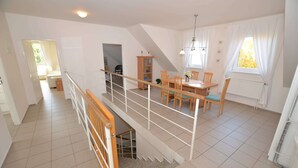 Un comedor espacioso con techo alto, una escalera y vistas al exterior.