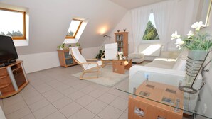 Una sala de estar moderna con un sofá, sillas, un televisor y una estantería.