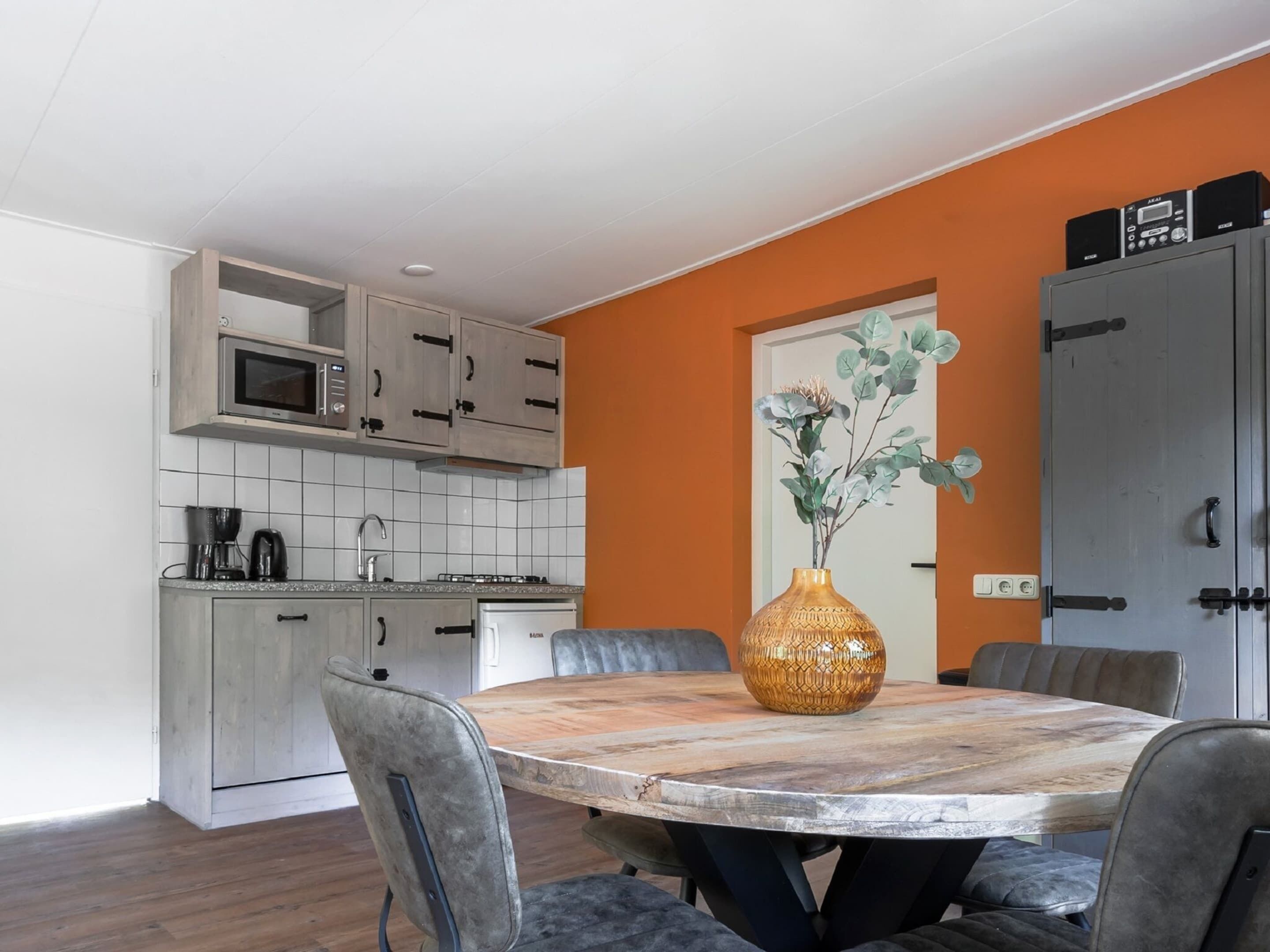 A modern kitchen with white cabinets, a microwave, and a stove. There is a dining table with chairs and a vase of flowers.