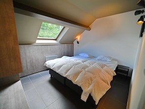A bedroom with a skylight, a bed with white bedding, a radiator, and a nightstand. - Well-kept Apartment With a Dishwasher not far From Durbuy (Durbuy)