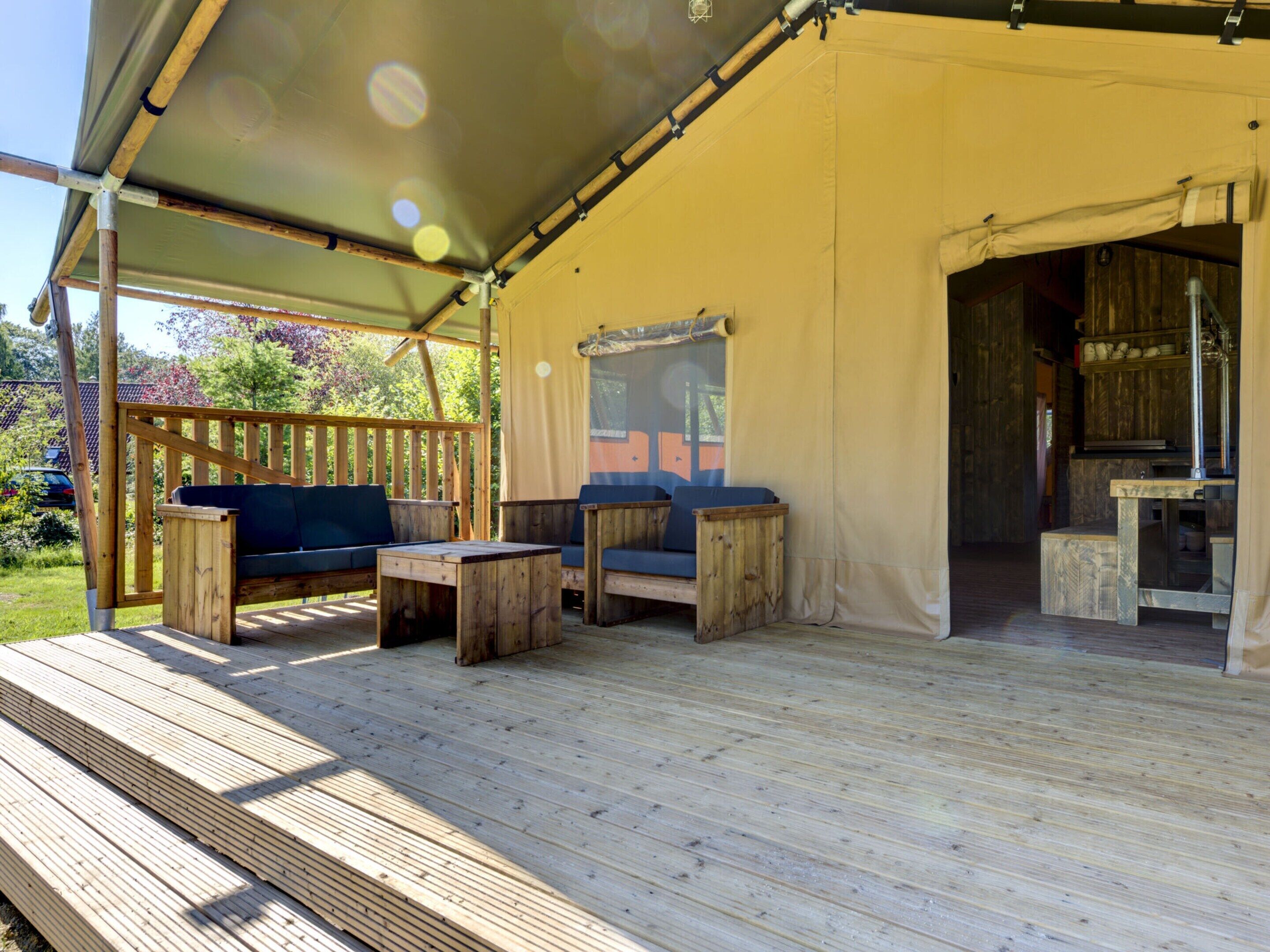 A covered outdoor seating area with wooden furniture and a view of the surrounding garden.