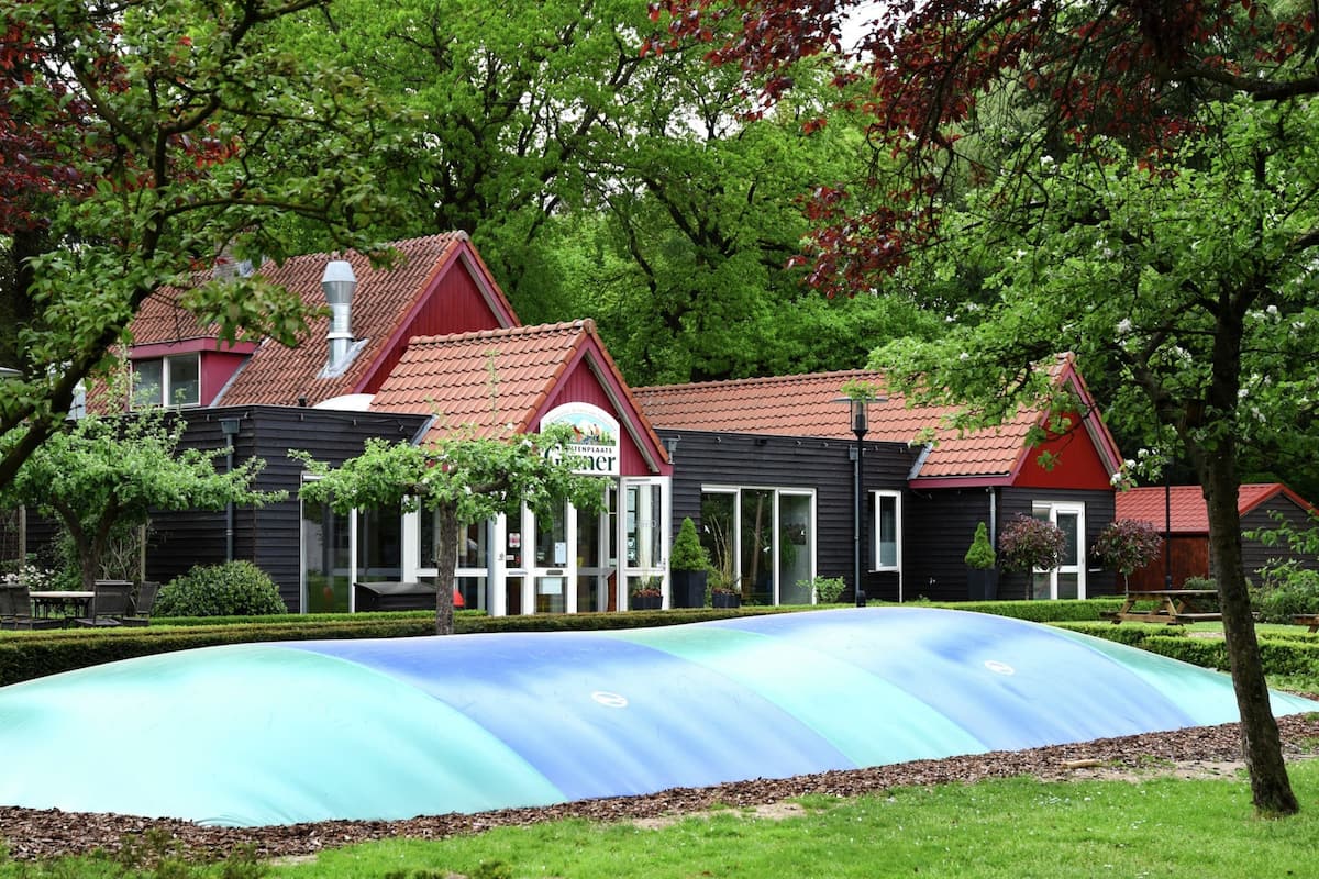 Ein traditionelles niederländisches Gebäude mit rotem Dach und Garten vor der Fassade.