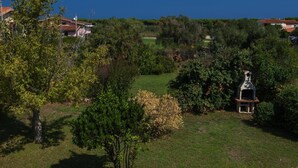 A lush garden with a variety of trees and shrubs, a small gazebo, and a clear view of the surrounding landscape.