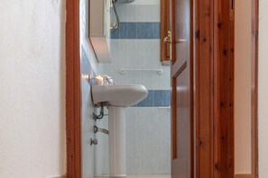 Ein Badezimmer mit einem weißen Waschbecken, einem Spiegel und einer Duschkabine.