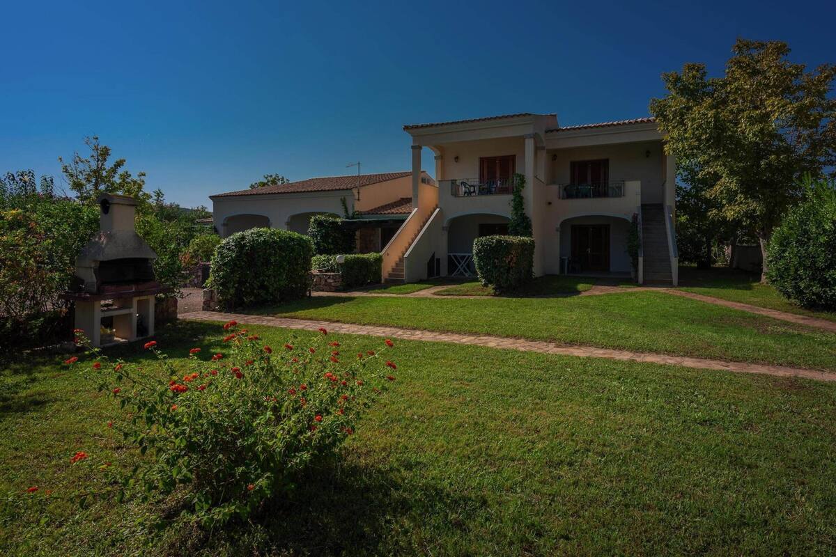 A two-story house with a patio, a chimney, and a well-maintained lawn.