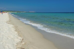 A beach with clear turquoise water, sandy shore, and distant hills. - Holiday Resort, Budoni (Budoni)
