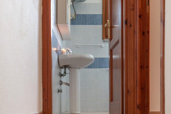 A bathroom with a white sink, a mirror, and a shower area. - Holiday Resort, Budoni (Budoni)