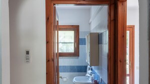 A bathroom with a wooden door frame, a window, a sink, and a mirror.
