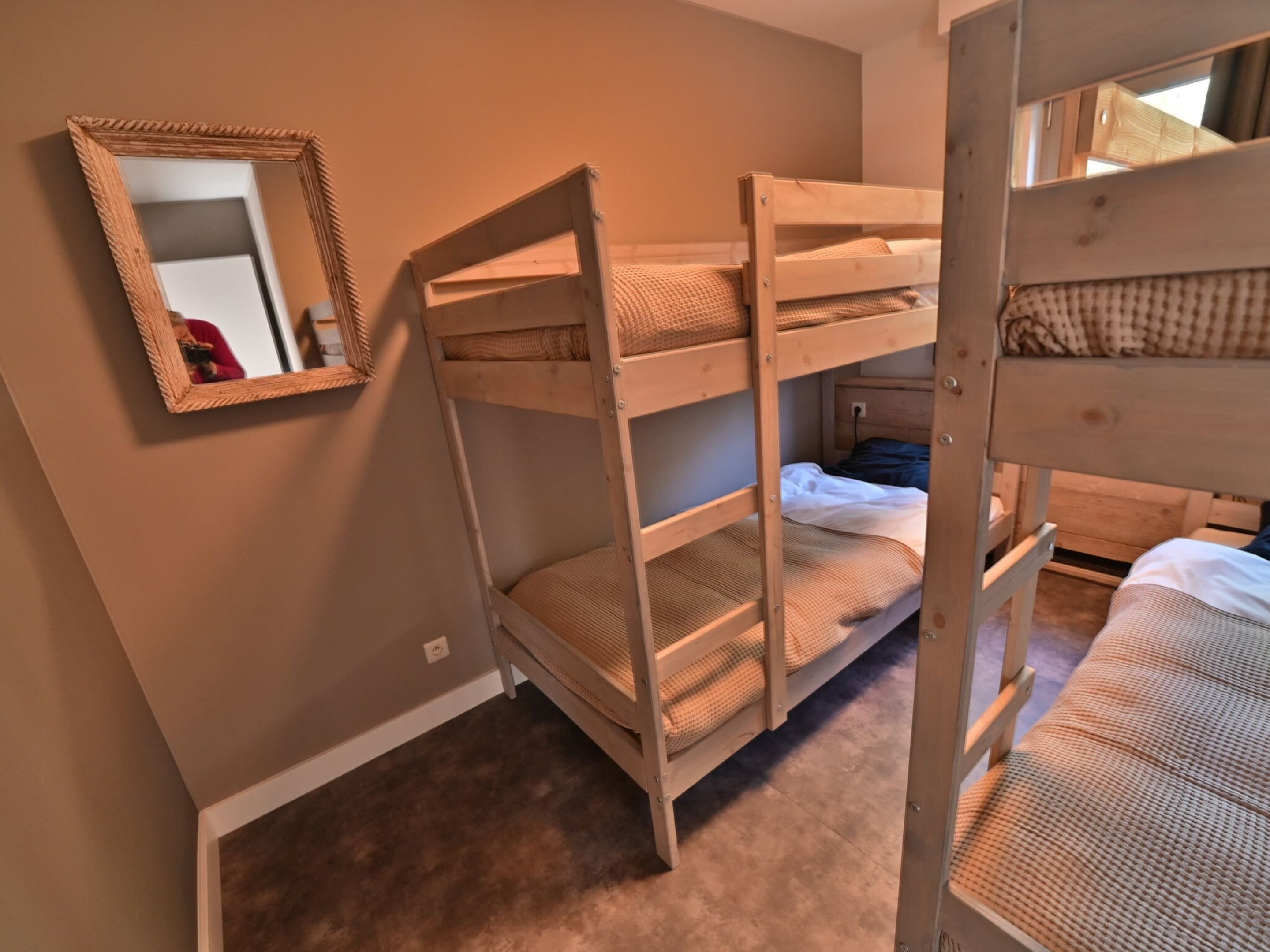 A bunk bed room with a mirror on the wall.