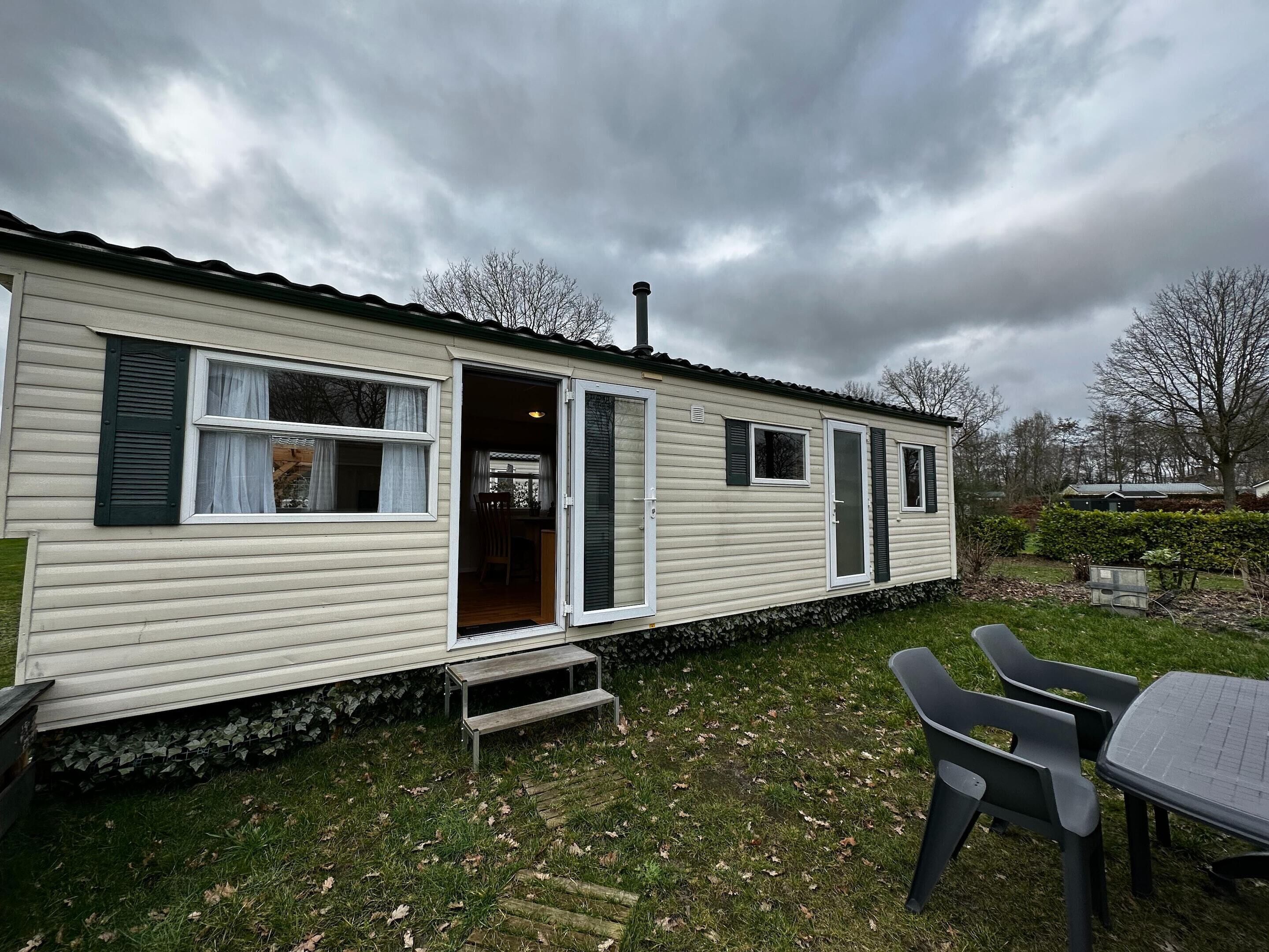 A mobile home with a patio area, including a table and chairs, and a small entryway.