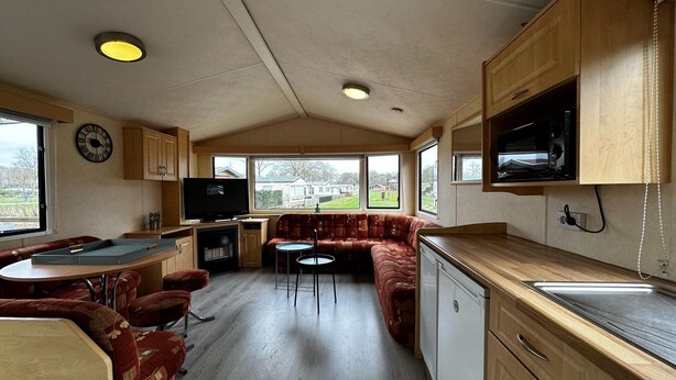 Ein kompaktes Wohnmobil-Interieur mit Küchenzeile, Essbereich, Sitzecke mit Sofa und Fernseher.