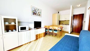 A compact living space with a kitchenette, a dining area, and a sofa. - Modern Apartment in Caorle With Private Terrace (Caorle)