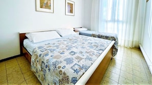 A bedroom with two beds, a large window with sheer curtains, and two framed pictures on the wall. - Modern Apartment in Caorle With Private Terrace (Caorle)