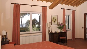 A bedroom with a bed, a desk, and a window with curtains.
