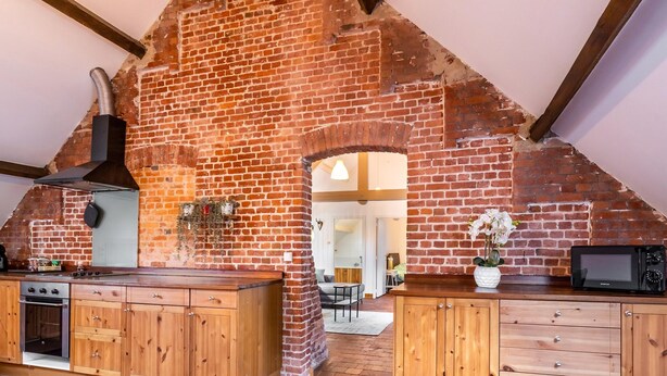 A kitchen with wooden cabinets, a stove, and a brick wall. - Nice Apartment on Unesco World Heritage Site Wortel-kolonie (Hoogstraten)