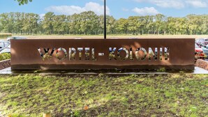 A sign with the text "VORIL-KOLONII" in a metal structure. - Nice Apartment on Unesco World Heritage Site Wortel-kolonie (Hoogstraten)