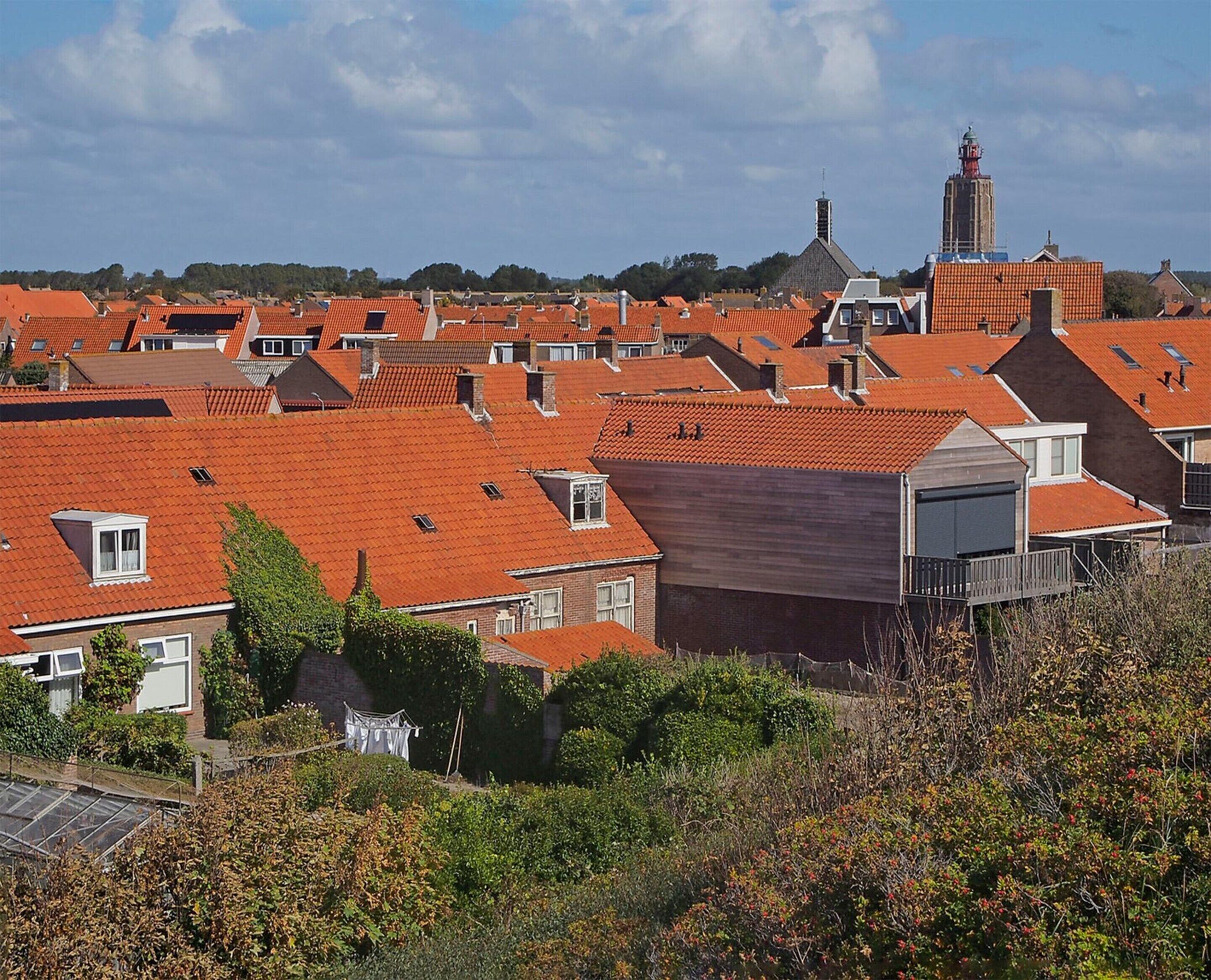 Et boligområde med røde tegltage, et markant kirktur og frodig vegetation.