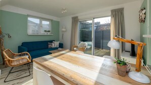 A living room with a blue sofa, wooden coffee table, wicker chairs, and a desk lamp. - Holiday Home With sun Terrace Facing South-pet-friendly (Westkapelle)