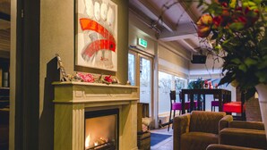 A cozy lounge area with a fireplace, comfortable seating, and a large window providing a view of the outdoors. - Wellness Lodge With Sauna and Wonderful Views (Zuna)