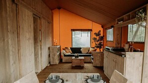 A cozy cabin interior with a dining table set for four, wooden walls, a sofa, and a kitchen area. - Wellness Lodge With Sauna and Wonderful Views (Zuna)