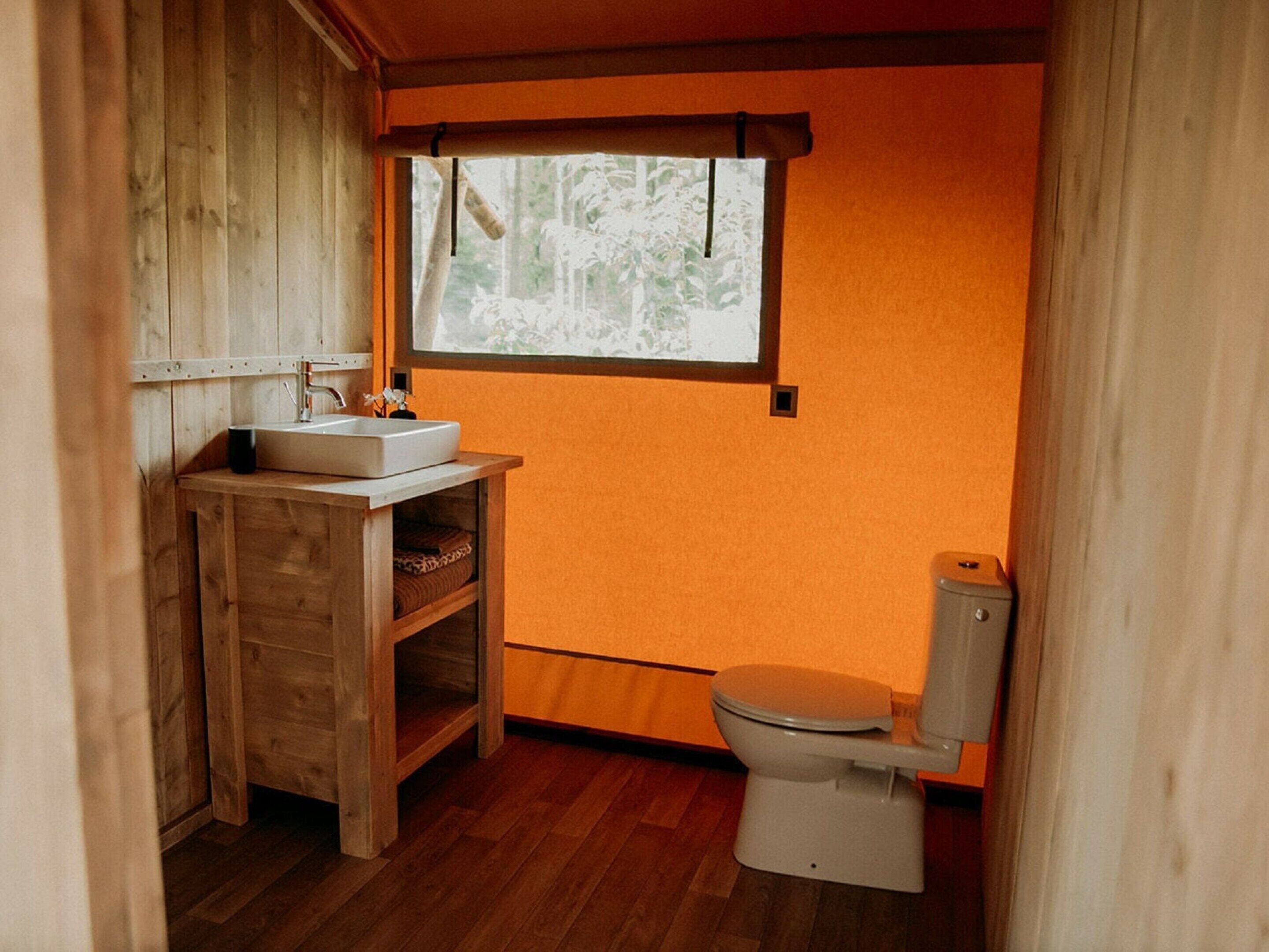 A compact bathroom with a wooden vanity, a white sink, and a toilet.