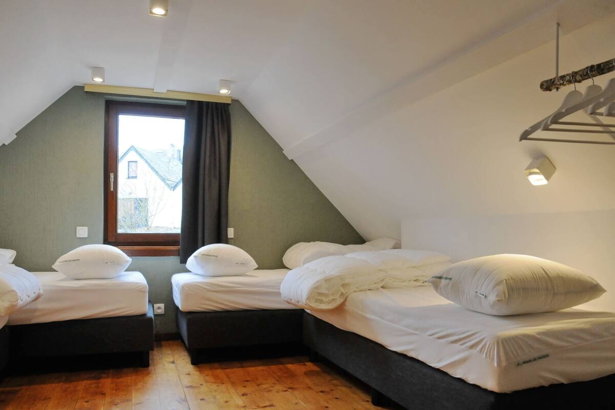 Una habitación con dos camas, una ventana y piso de madera.