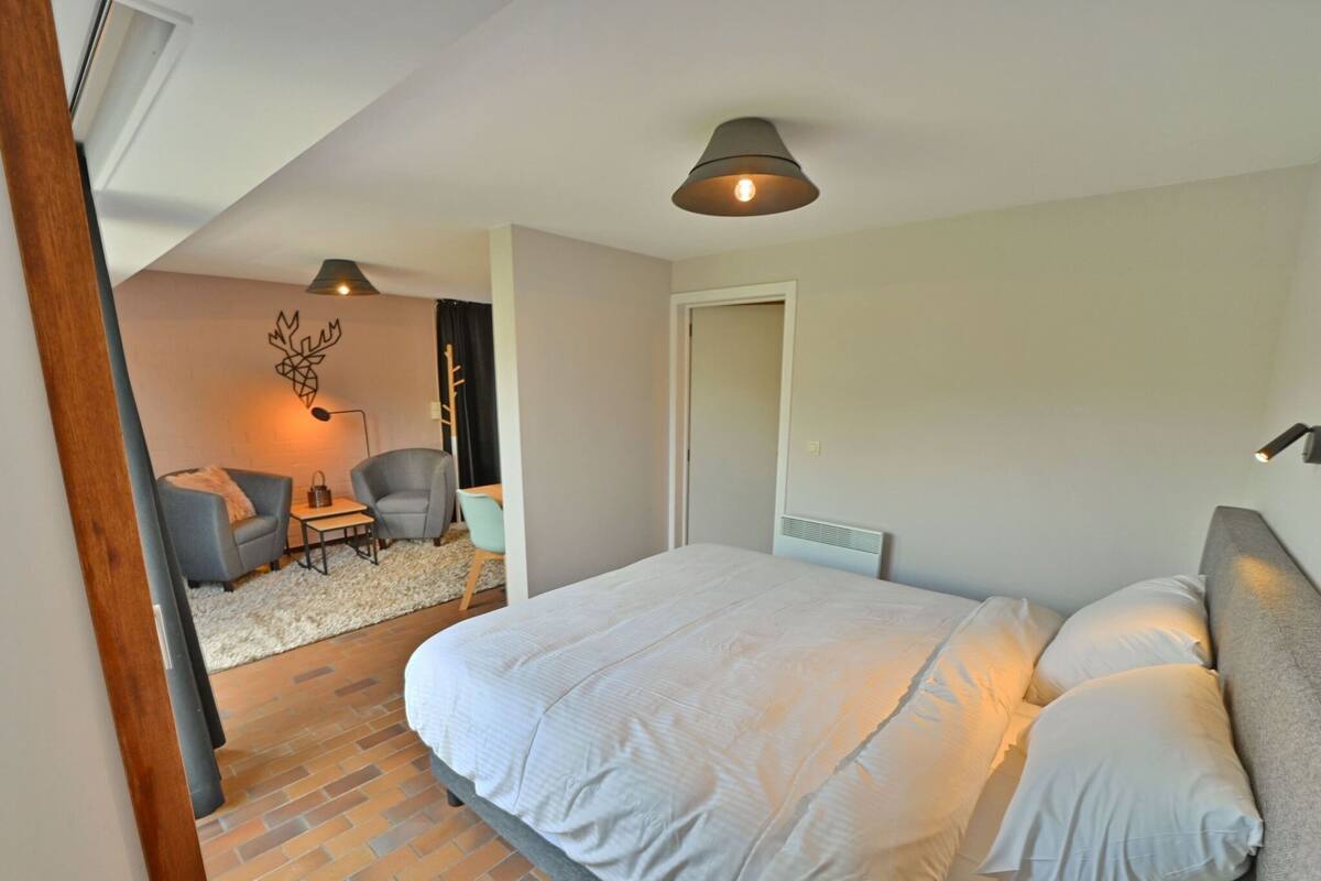 Un dormitorio con una cama grande, un escritorio y dos sillas. Hay una puerta que conduce a otra habitación.