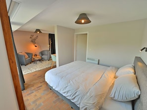 A bedroom with a large bed, a desk, and two chairs. There is a door leading to another room. - Comfortable, Renovated House With a Microwave, Near Vielsalm (Vielsalm)