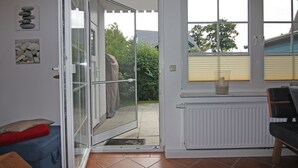 Et værelse med en skydedør til en patio, en radiator og et vindue med persienner.