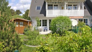 Et toetagers hus med balkon, lille have og et træskur.
