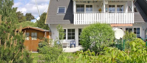 A two-story house with a balcony, a small garden, and a wooden shed.