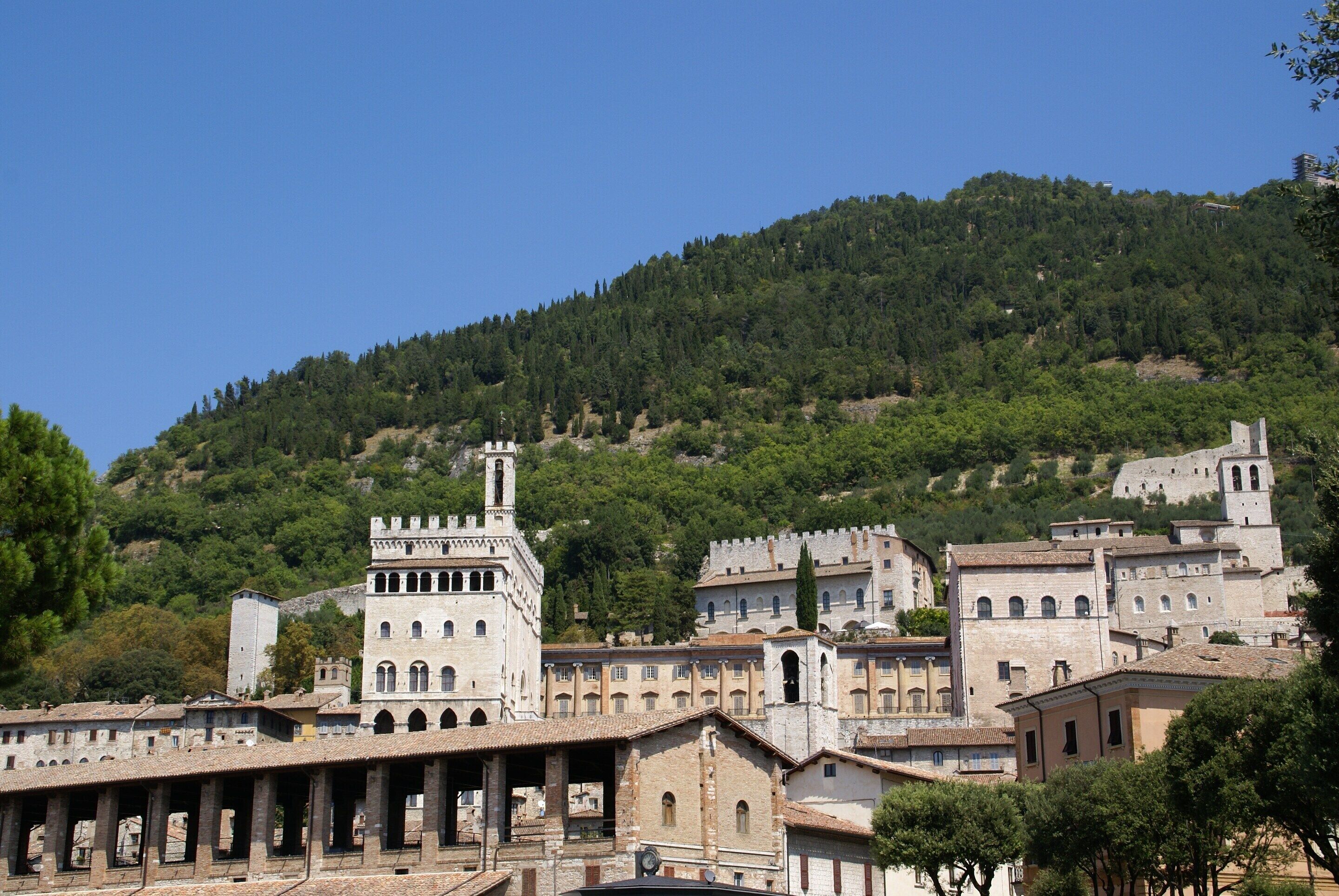 A historic town with medieval architecture, including a prominent tower and a series of arches.