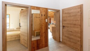 A room with a wooden door, a bed, and a bench. - Top Holiday Home in Kleinarl Near Cross-country Ski Trail (Kleinarl)