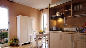A compact kitchen with a dining area, a view through a sliding door, and a balcony with a plant. - Apartment in San Bartolomeo Al Mare (San Bartolomeo al Mare)