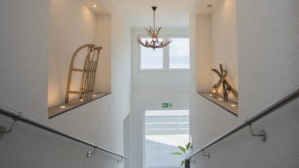 A modern interior with a staircase, metal railings, a chandelier, and a window with a view. - Modern Flat in Neuastenberg With Balcony (Winterberg)