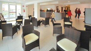 Un hall d’entrée avec des fauteuils en osier, un comptoir de réception et une porte vitrée donnant sur l’extérieur.