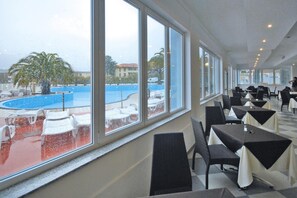 A restaurant with large windows overlooking a pool area. - Holiday Resort Ai Pozzi Village Resort, Loano (Loano)