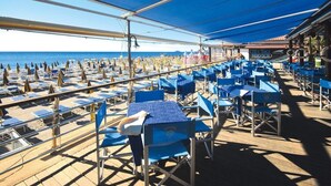 Ein Restaurant am Strand mit Außenbereich, Sonnenschirmen und Meerblick.