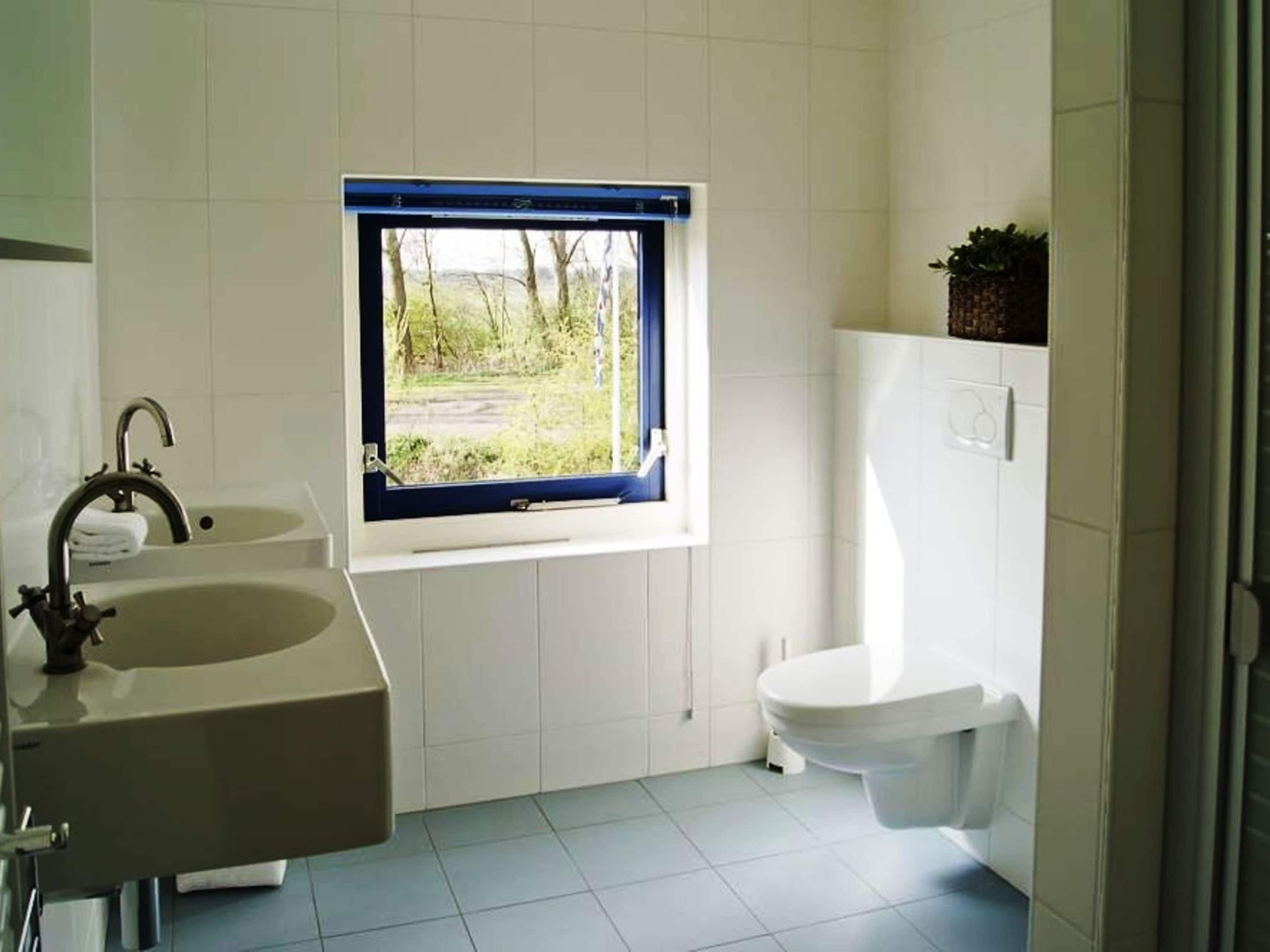 Un baño con ventana, lavamanos y retrete.