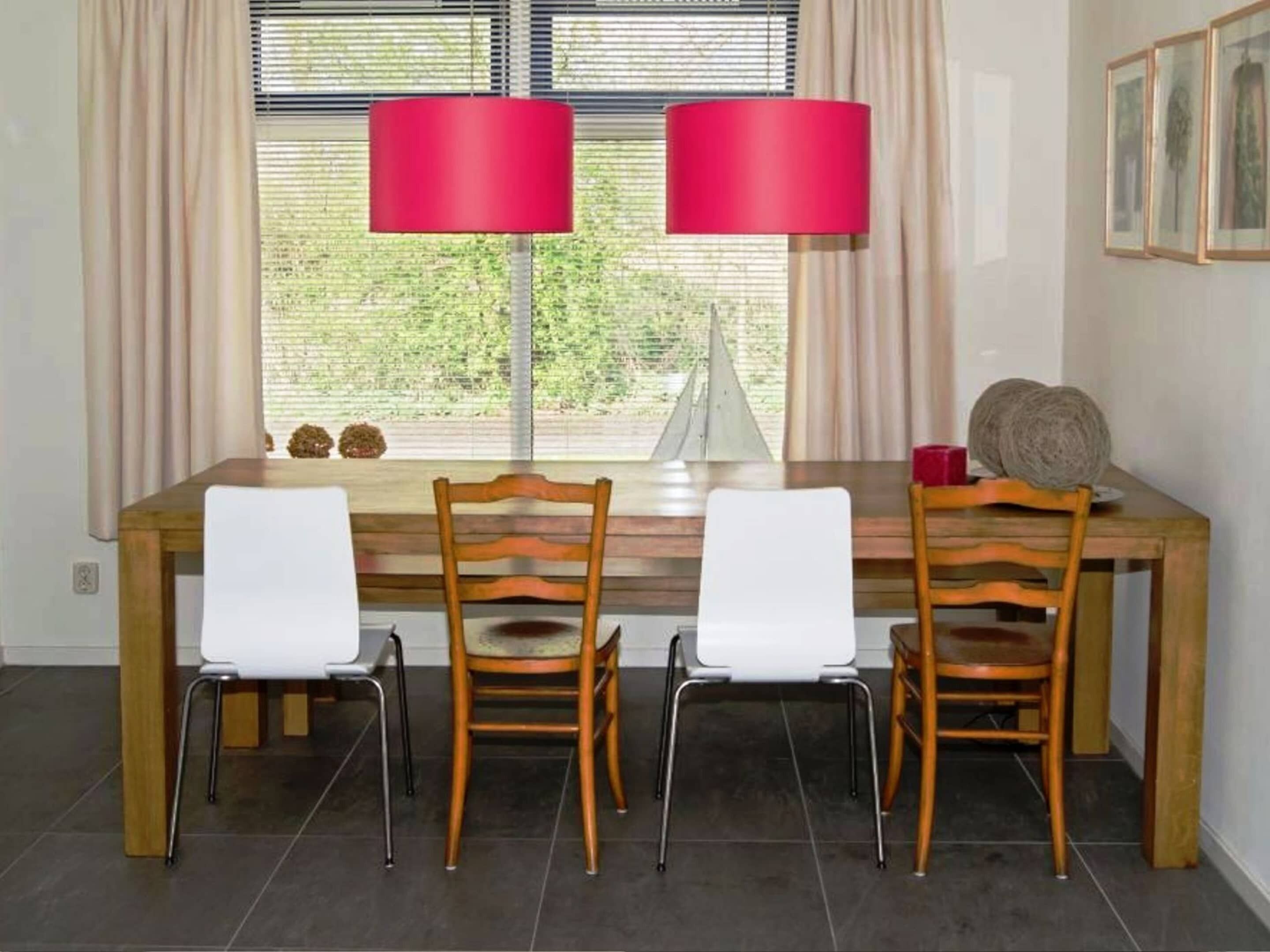 A dining area with a wooden table, two chairs, and two red lamps.