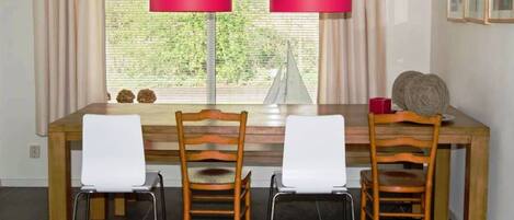 A dining area with a wooden table, two chairs, and two red lamps.