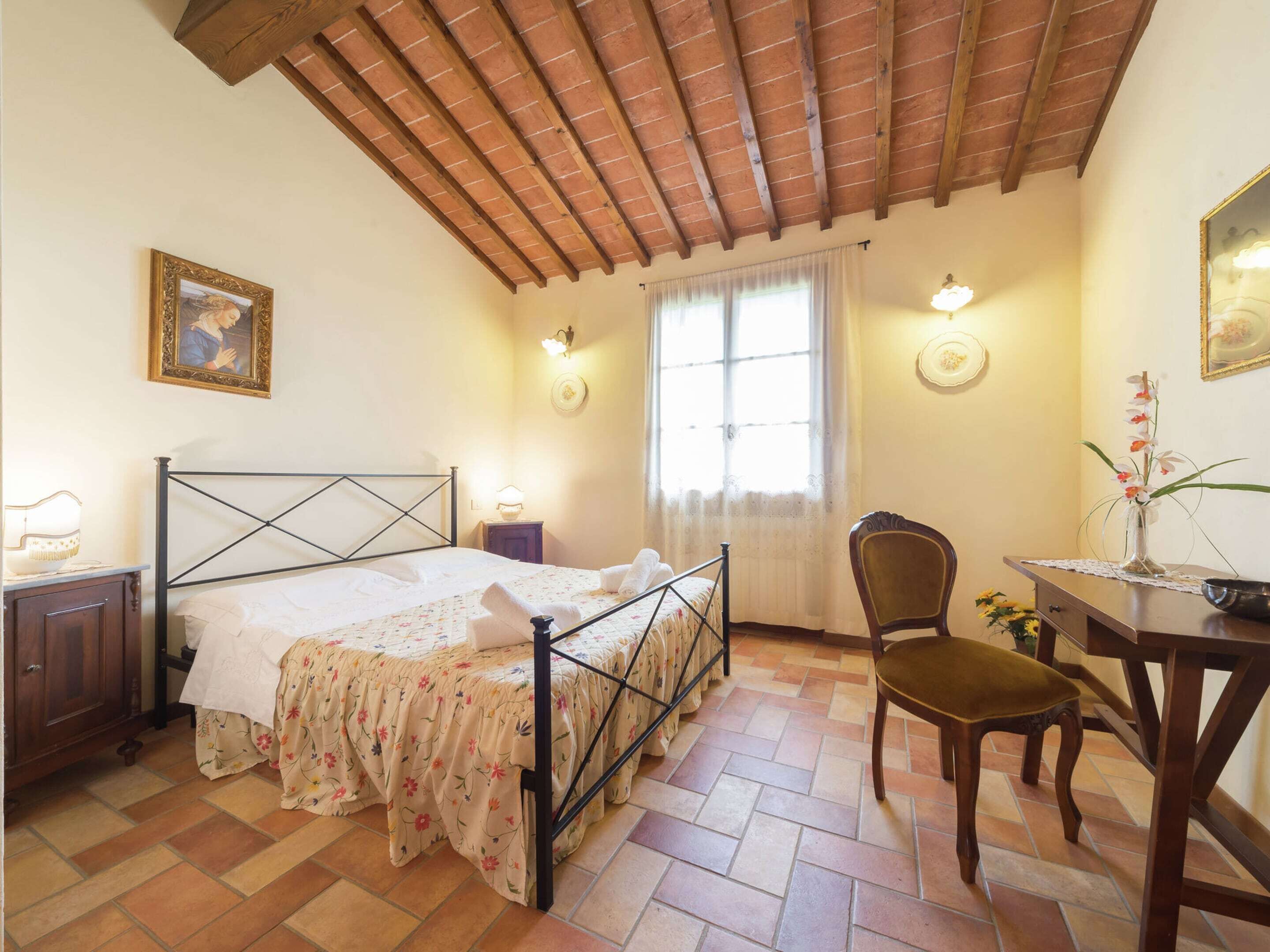 A bedroom with a bed, a chair, a table, and a window.